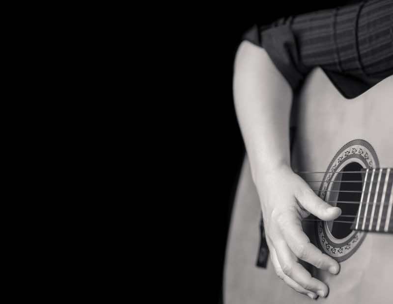 Acoustic guitar detail on black and white - Musician hands playi