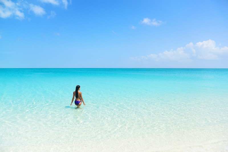 Beach holiday person swimming in blue ocean. Sexy bikini woman r