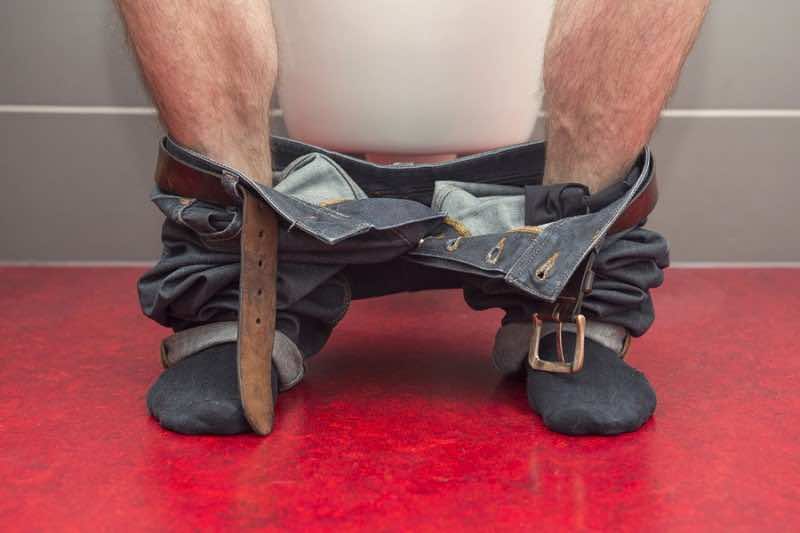 closeup of man with jeans sitting on a toilet