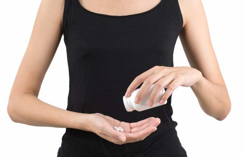 woman pouring pills in hand from bottle isolated on white background.