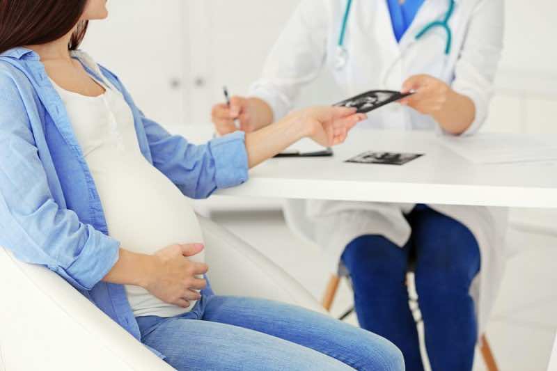 Gynecologist giving echo photo to pregnant woman