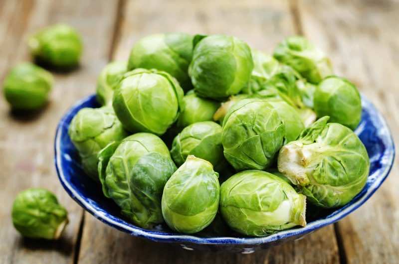 Brussels sprouts in a wooden bowl on wood background