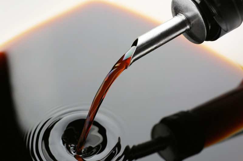 Pouring tasty soy sauce from bottle, closeup